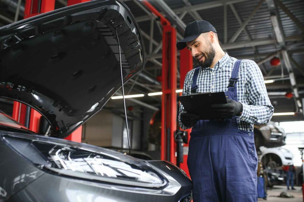 Professional mechanic conducting a third party inspection with a clipboard near an open engine bay.