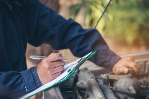 Auto expert filling out a checklist to check used car service Houston providers for a pre-purchase inspection.